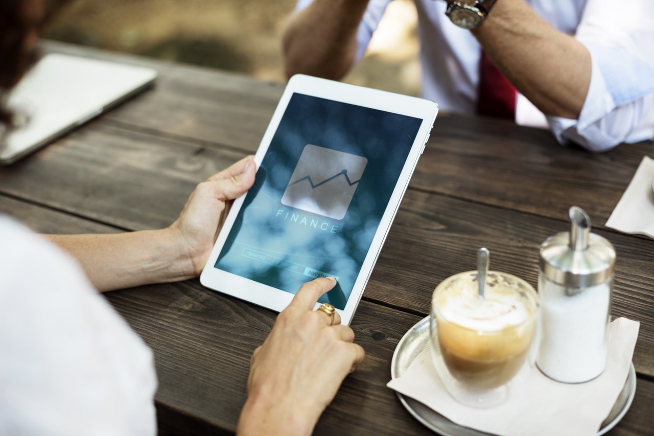 A person sitting at a wooden bench holding a tablet 