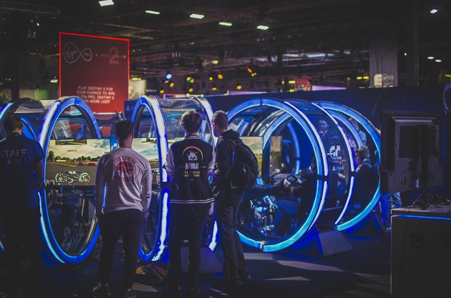 3 men standing in front of racing arcade machines 3 men standing in front of racing arcade machines