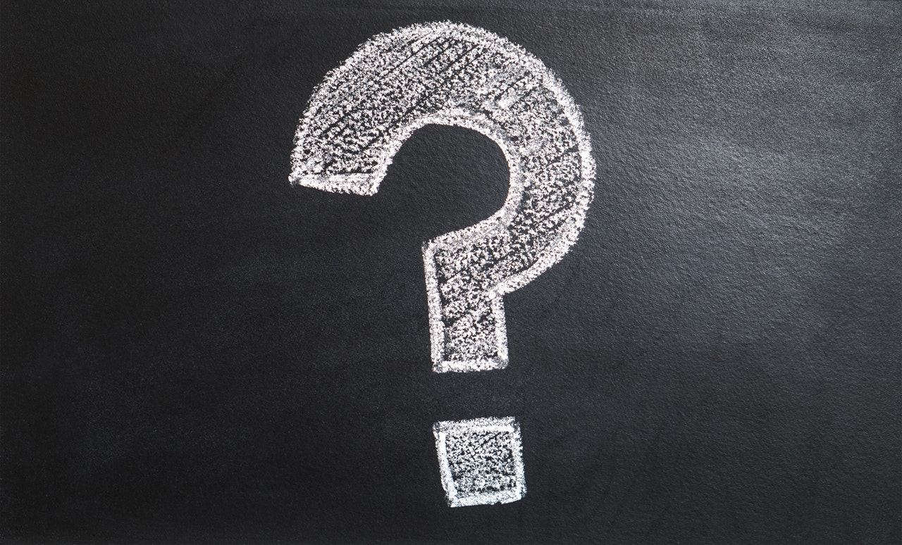 A chalked white question mark on a black surface A chalked white question mark on a black surface