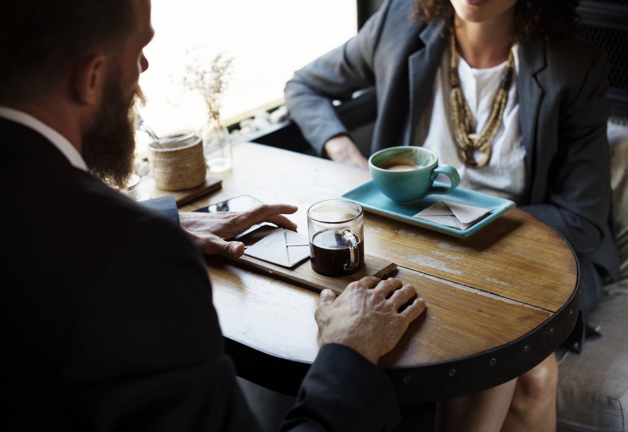 A man and woman sitting at a table drinking coffee A man and woman sitting at a table drinking coffee