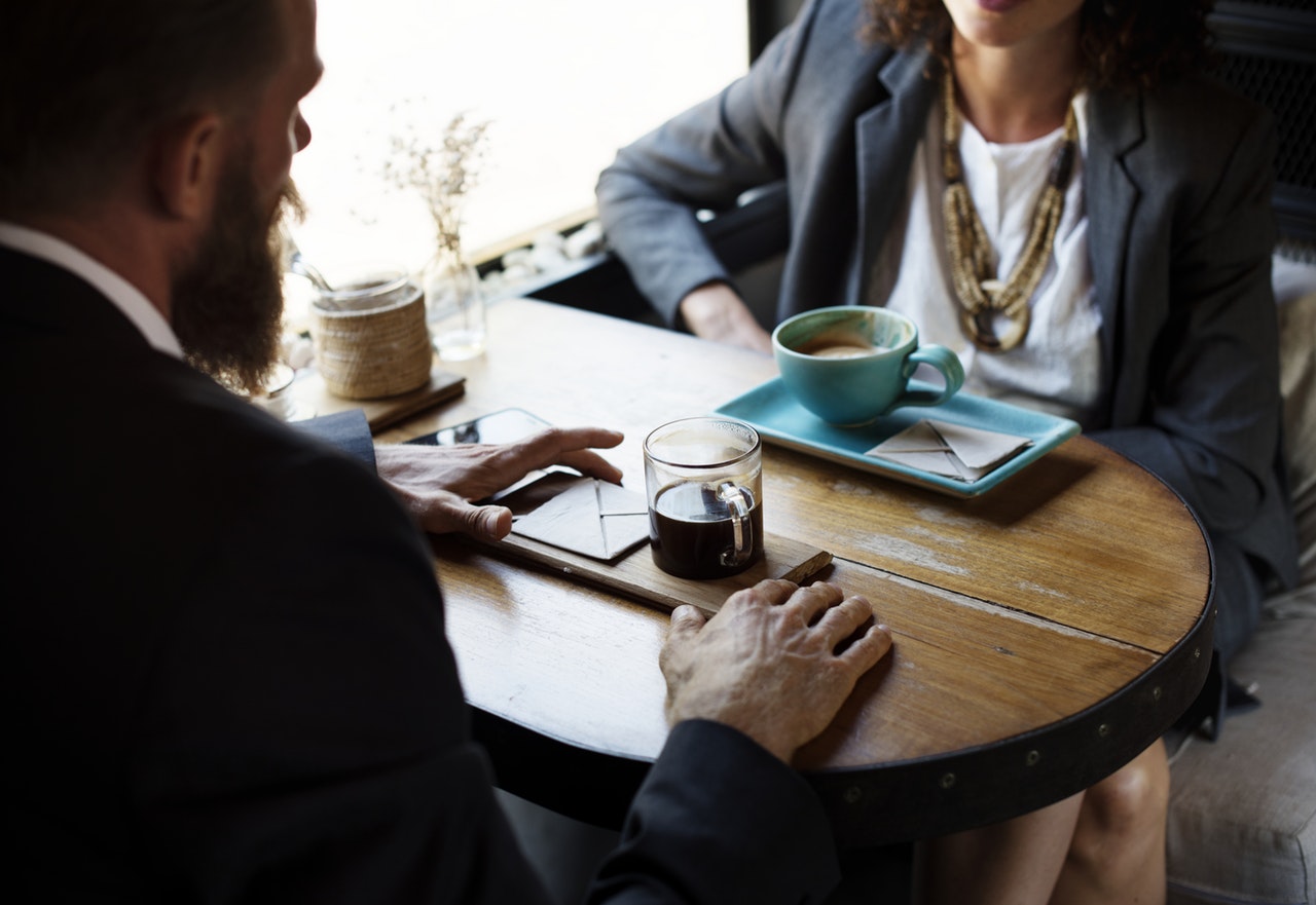 A man and woman sitting at a table drinking coffee