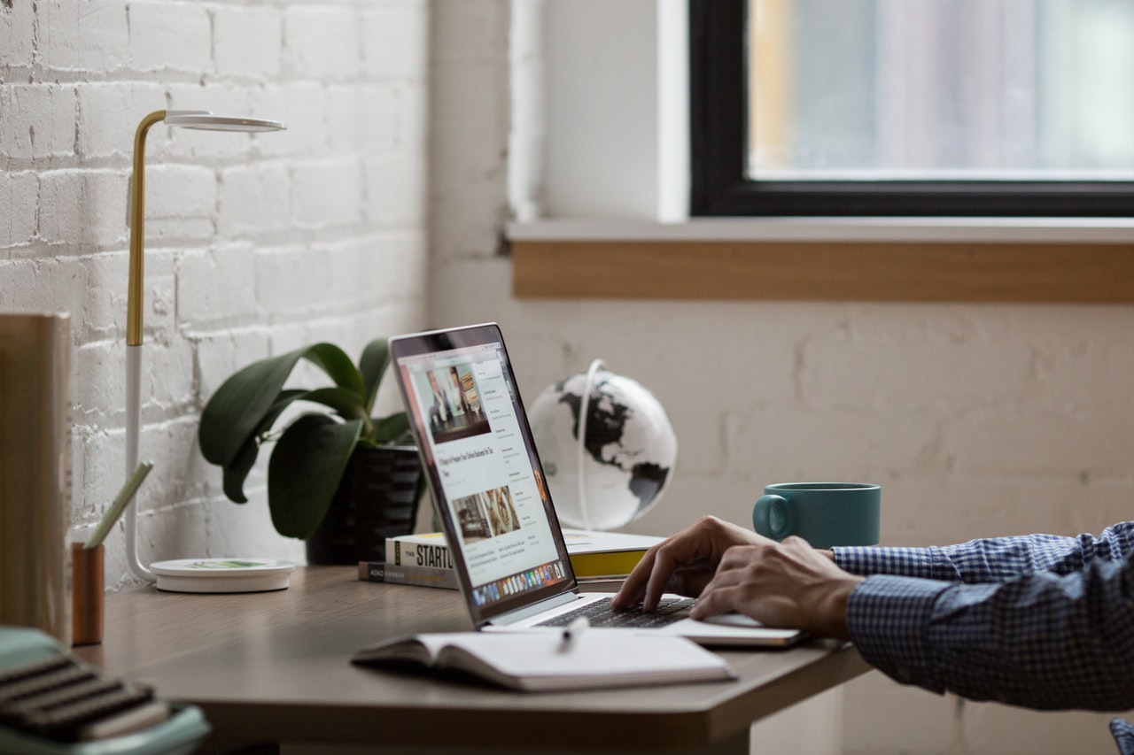 A man sitting at a laptop with a coffee cup beside him 