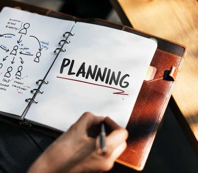 Image of a person writing in a file that says the word 'Planning' Image of a person writing in a file that says the word 'Planning'