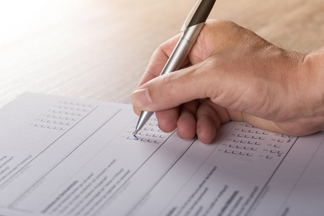 A man holding a pen and completing a tick-box survey