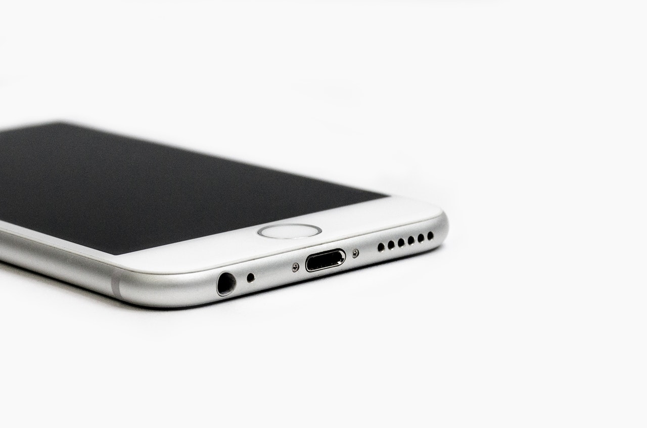 A close up of a silver iPhone phone against a white background