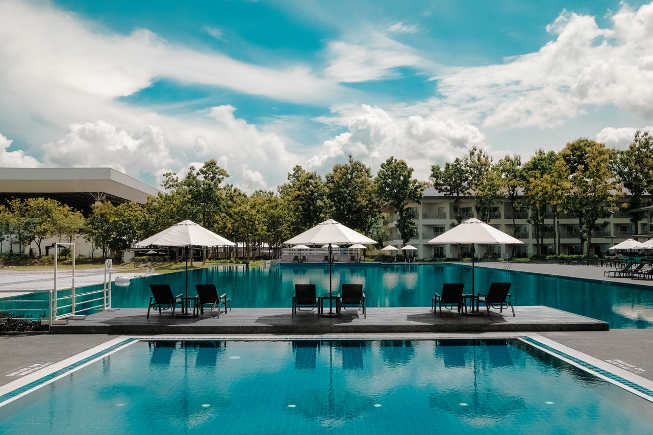 two swimming pools surrounded by sun loungers with white umbrellas two swimming pools surrounded by sun loungers with white umbrellas