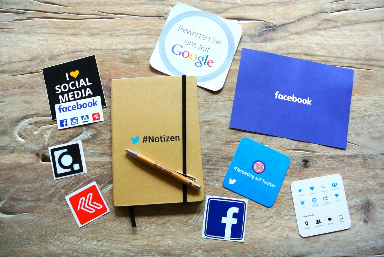 A wooden table with various social media related items on it including 2 coasters, stickers and a Twitter notebook and pen