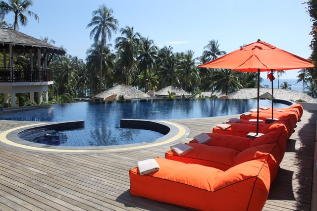 Orange loungers near swimming pool Orange loungers beside swimming pool