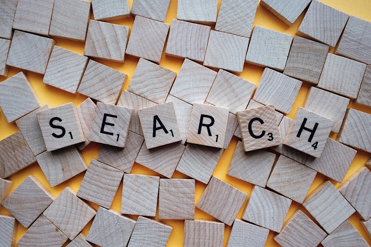 Scrabble cubes scattered on a wooden table with the word SEARCH spelt out in the middle