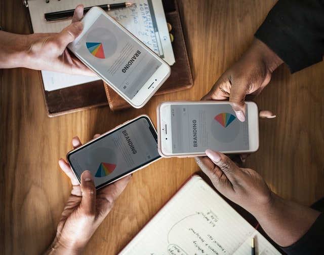 Three people holding phones displaying branding pie chart