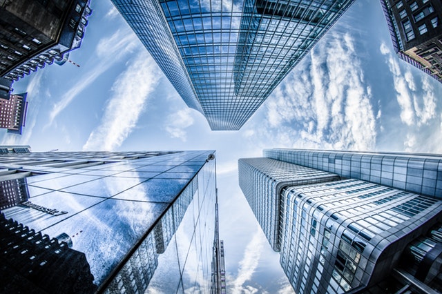 Low angle photo of four high-rise buildings under white clouds and blue sky