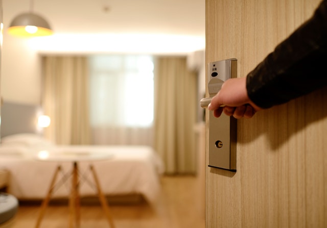 Person holding on door lever inside hotel room