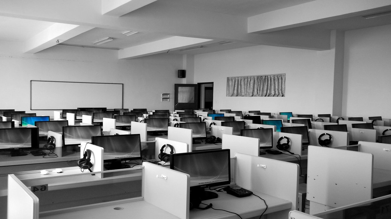 An empty office featuring row upon row of PCs, each with a set of headphones 