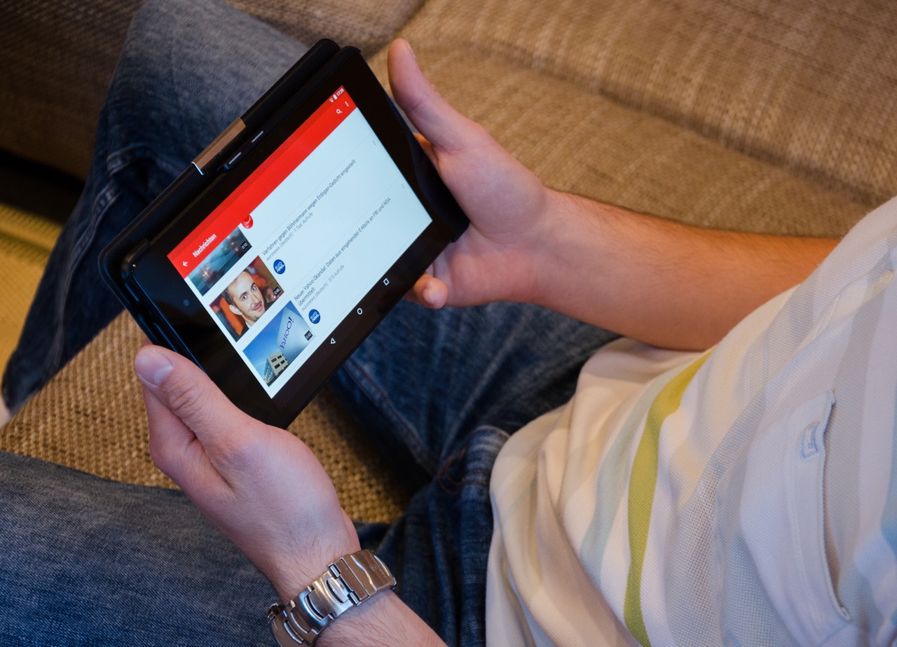 A man holding a tablet to the YouTube app