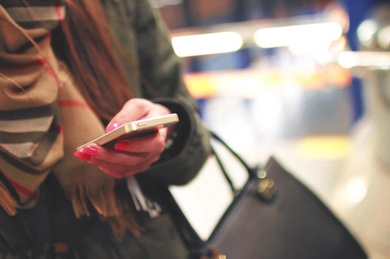 A woman holding a mobile phone in her left hand A woman holding a mobile phone in her left hand
