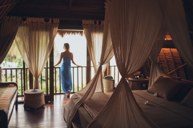 Woman looking out of window in hotel room 