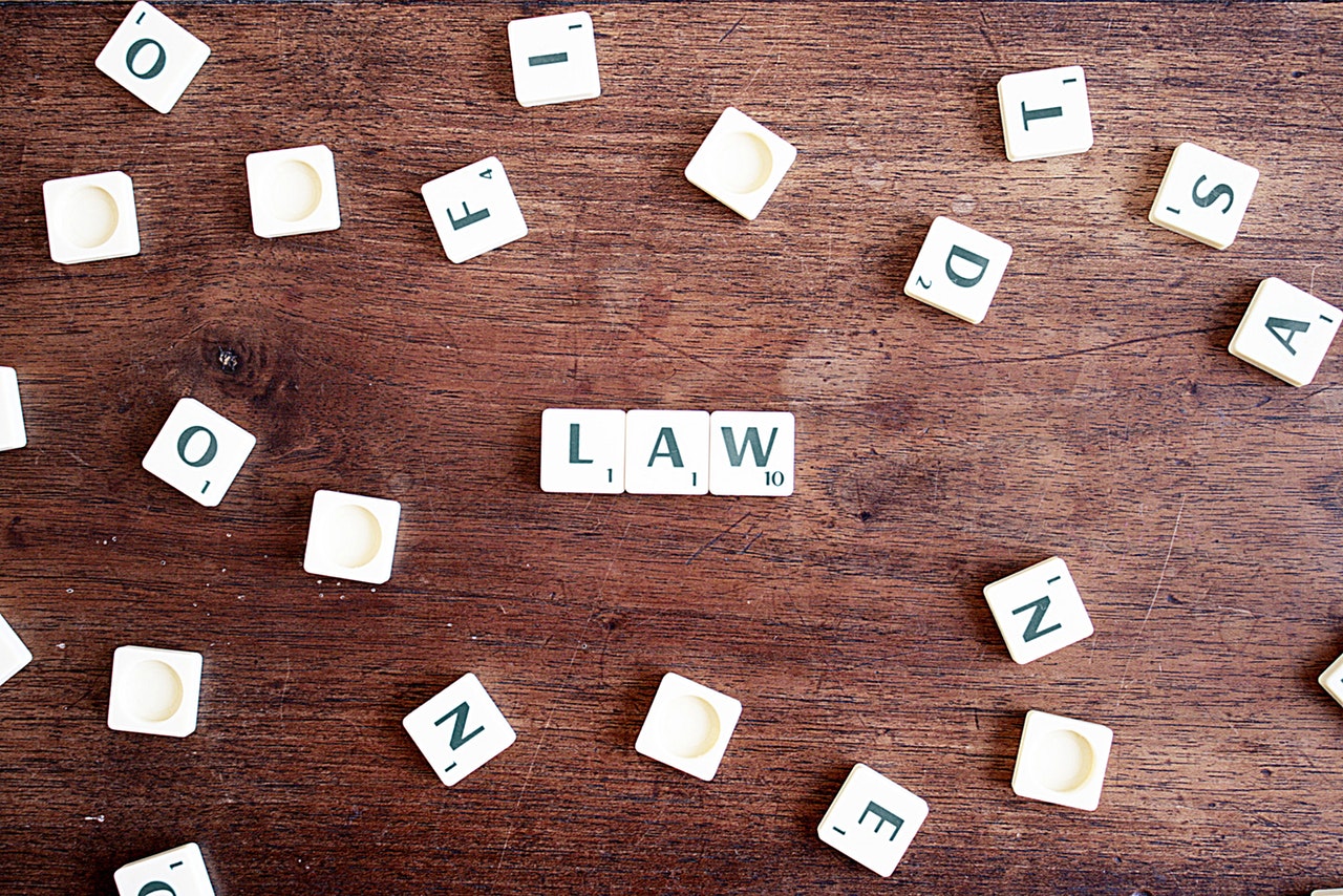 Scrabble cubes scattered on a wooden table with the word LAW spelt out in the middle