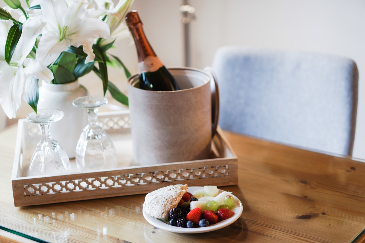 A wooden table with a glass of champagne in a bucket, 2 upturned glasses and a vase of white flowers A wooden table with a glass of champagne in a bucket, 2 upturned glasses and a vase of white flowers